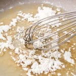 Flour and oil being mixed in a pan with a whisk.