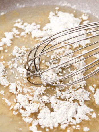 Flour and oil being mixed in a pan with a whisk.