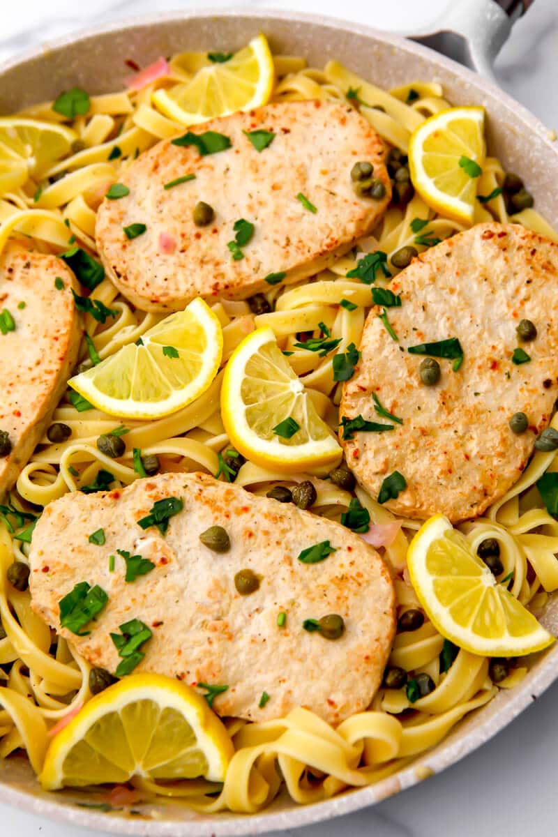 Vegan piccata with lemon and capers with vegan chicken on top in a fying pan.