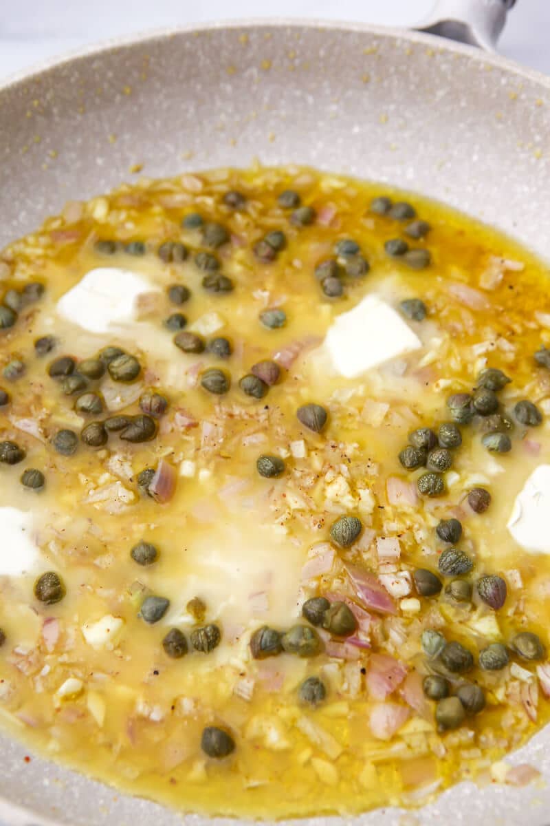 Vegan butter melting in piccata sauce with capers.