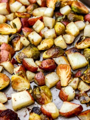 A close up of a roasted potatoes and Brussel sprouts on a sheet pan after baking.