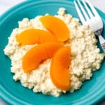 Vegan cottage cheese made from tofu on a blue plate with peach slices on top and a fork on the side.
