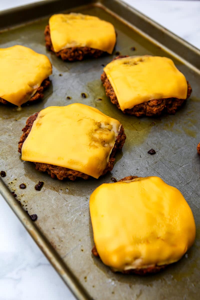 Slices of vegan cheese melted on top of vegan burger patties.