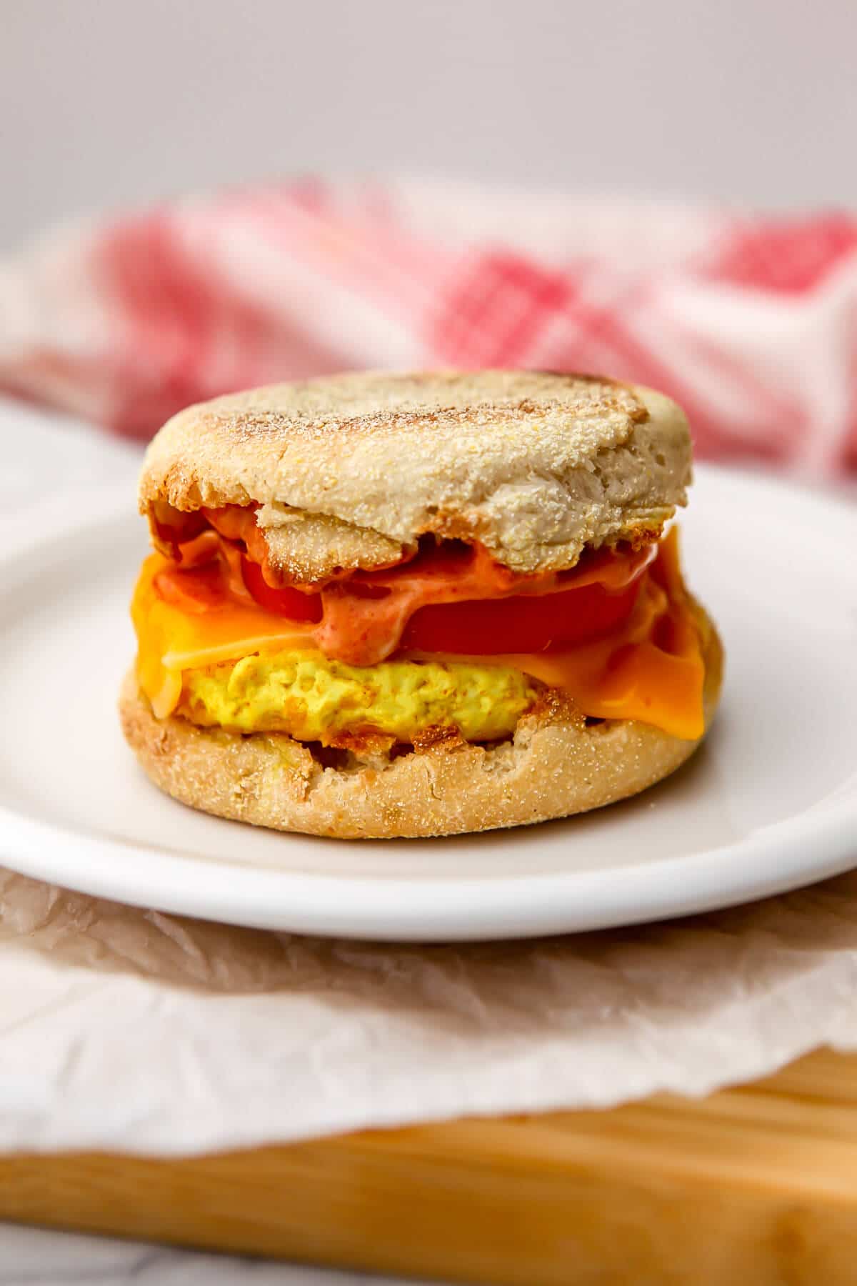 A tofu egg sandwich with cheese and tomato on a white plate.