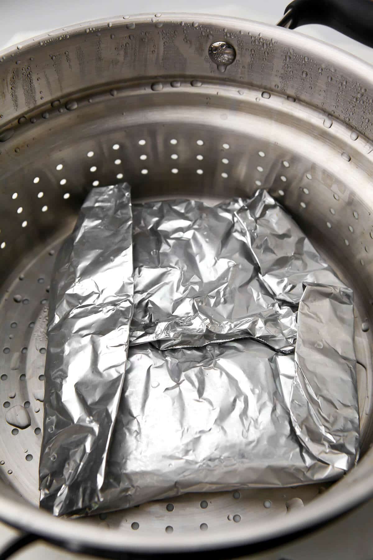 Seitan wrapped in foil in a steamer pot.