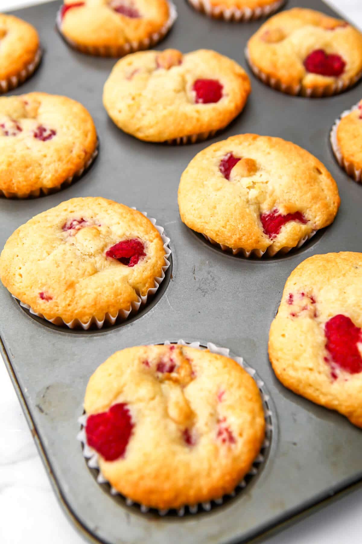 Baked raspberry muffins in a muffin tin.