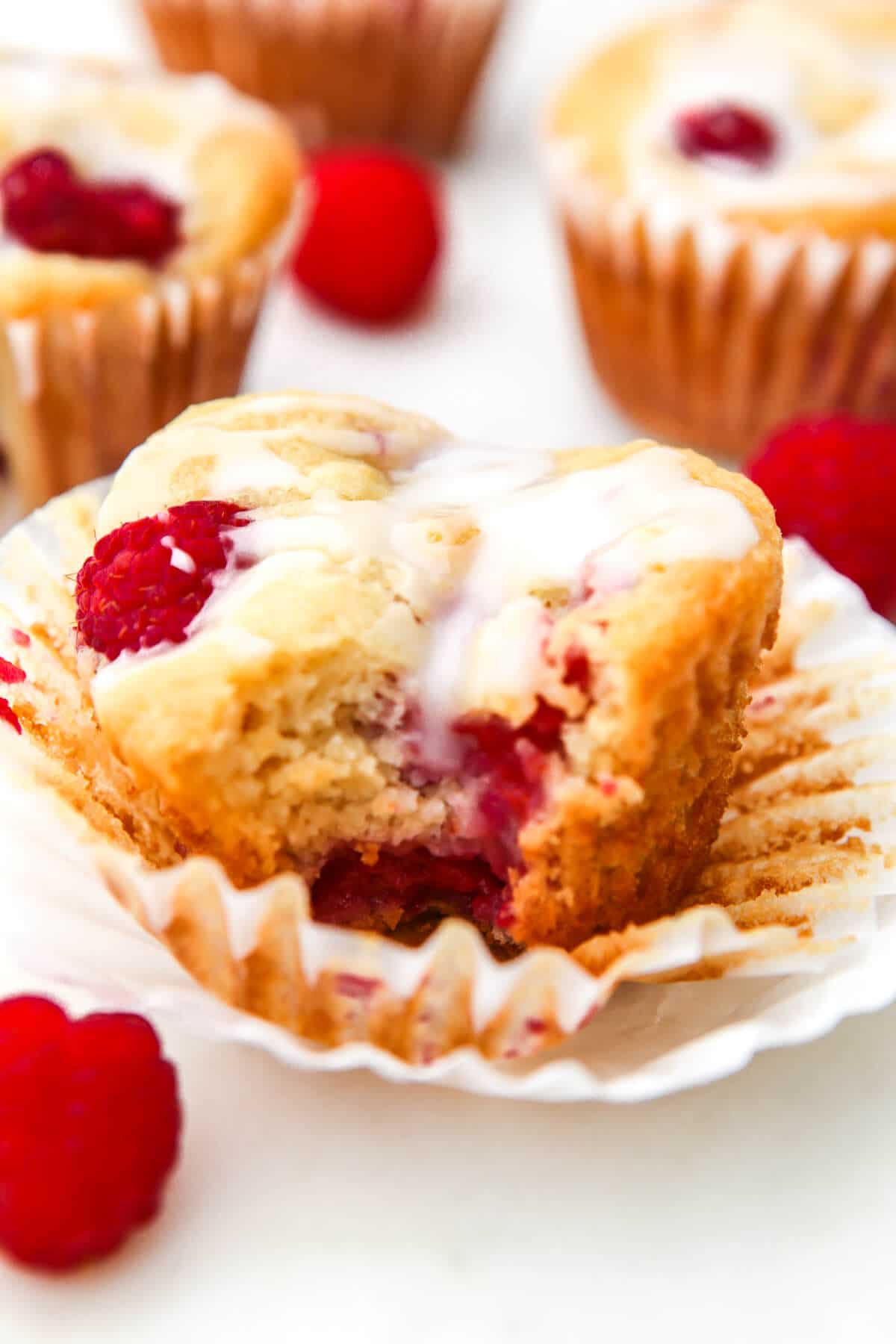 A vegan raspberry muffin with a bite taken out of it.