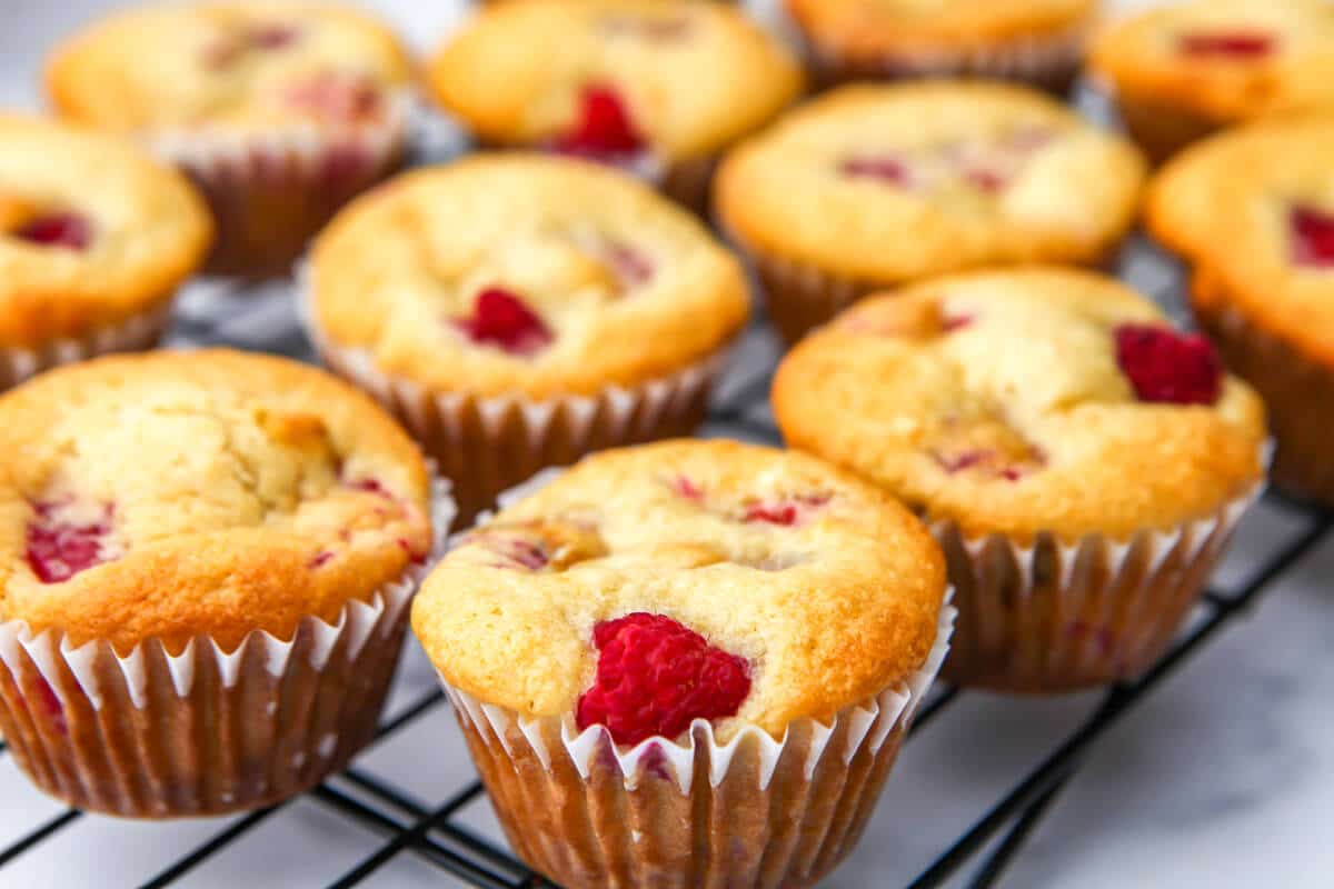 A dozen vegan raspberry muffins on a cooling rack.