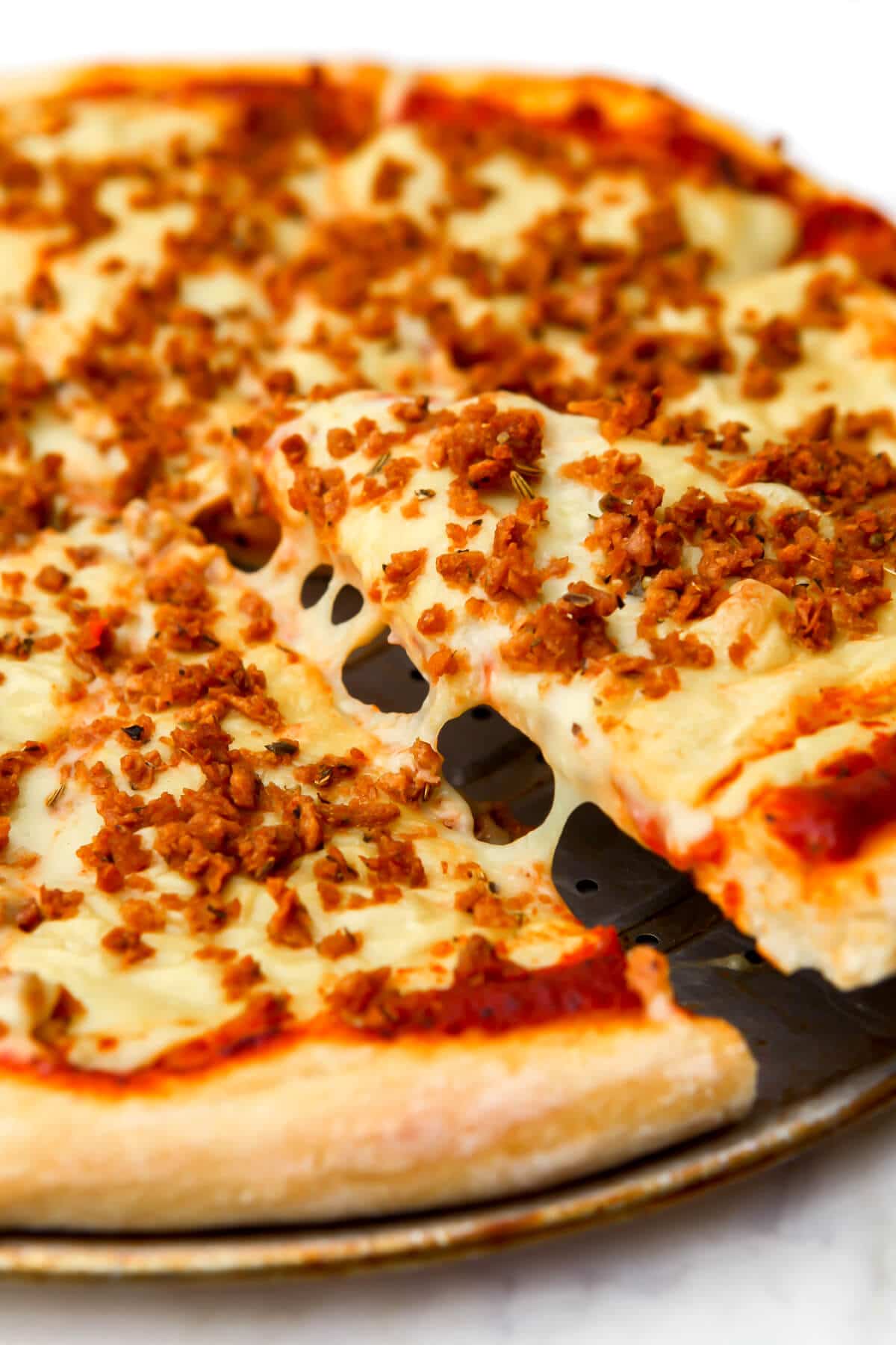 A vegan pizza topped with Italian style vegan sausage crumbles made with TVP.