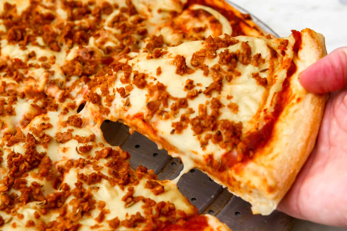 A vegan pizza covered in vegan sausage crumbles made with TVP.