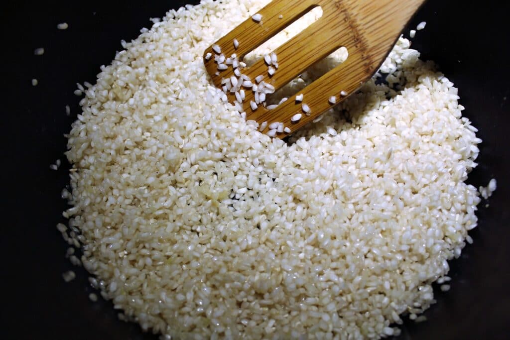 A skillet of rice browning being coated in melted butter.
