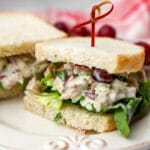 A vegan chicken salad sandwich on white bread sliced in half on a white plate.