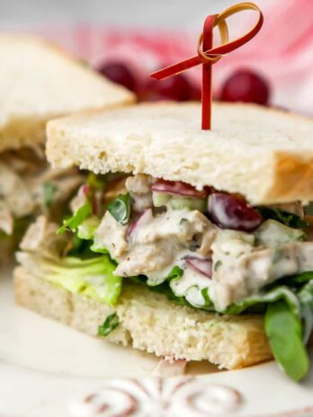 A vegan chicken salad sandwich on white bread sliced in half on a white plate.