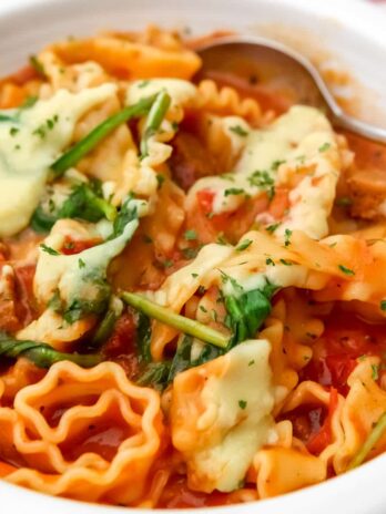 A close up of a bowl of vegan lasagna soup with white sauce drizzled on top.