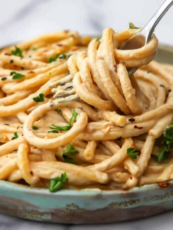 Tahini pasta with parsley on to being twirled up in a fork.
