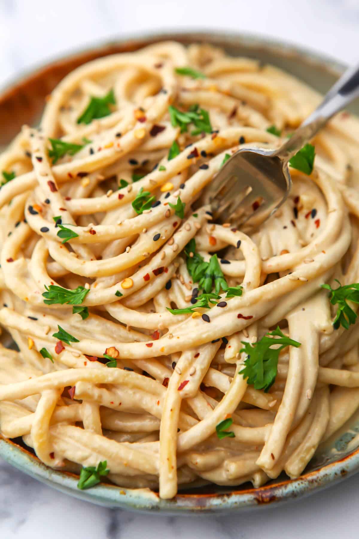 A top view of creamy tahini pasta with parsley on top.