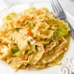 A plate filled with vegan haluski made with cabbage and noodles with a fork on the side.