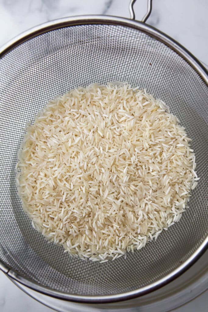 Rinced Basmati rice in a wire mesh strainer.