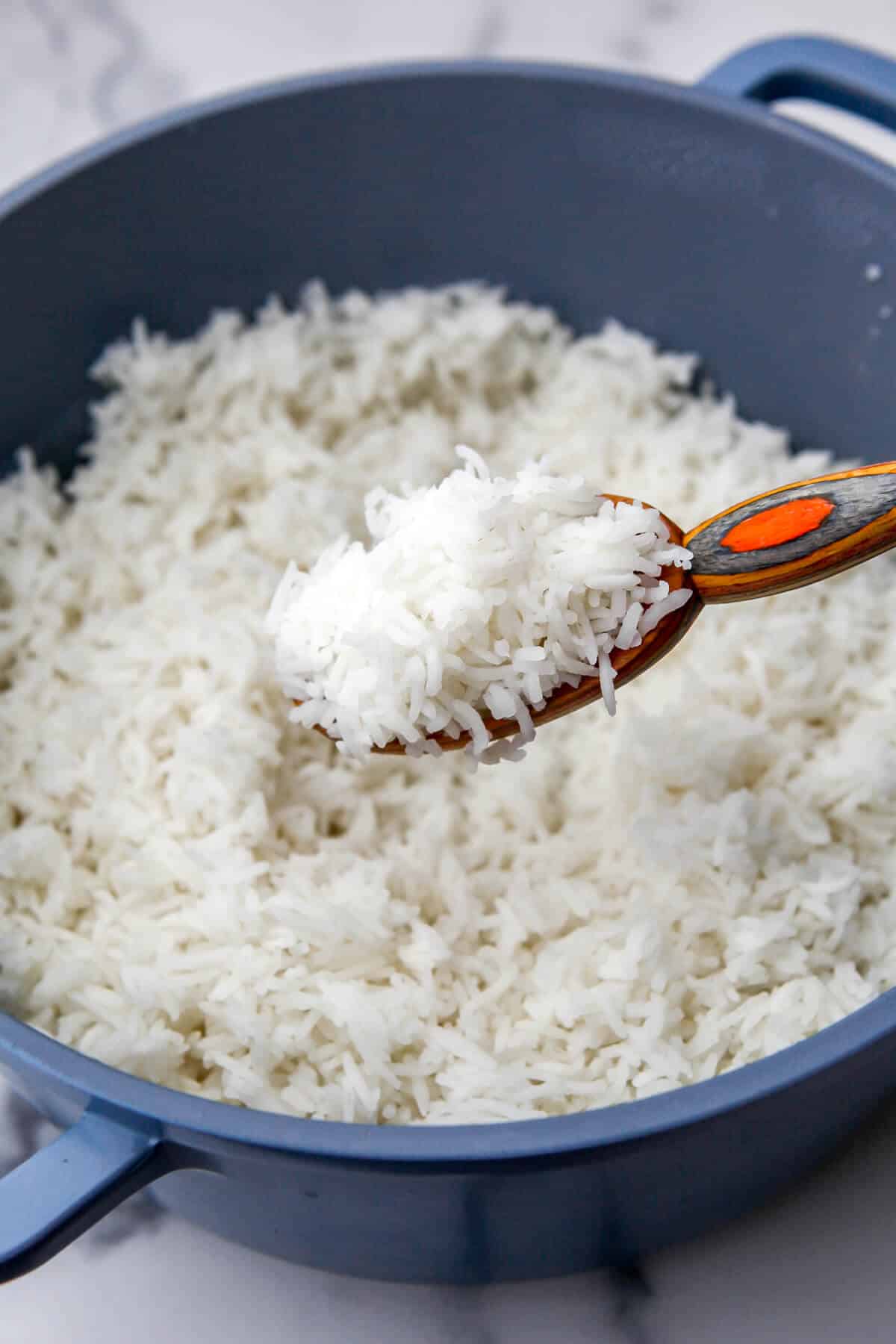 A blue pot filled with fluffy cooked Basmati rice.
