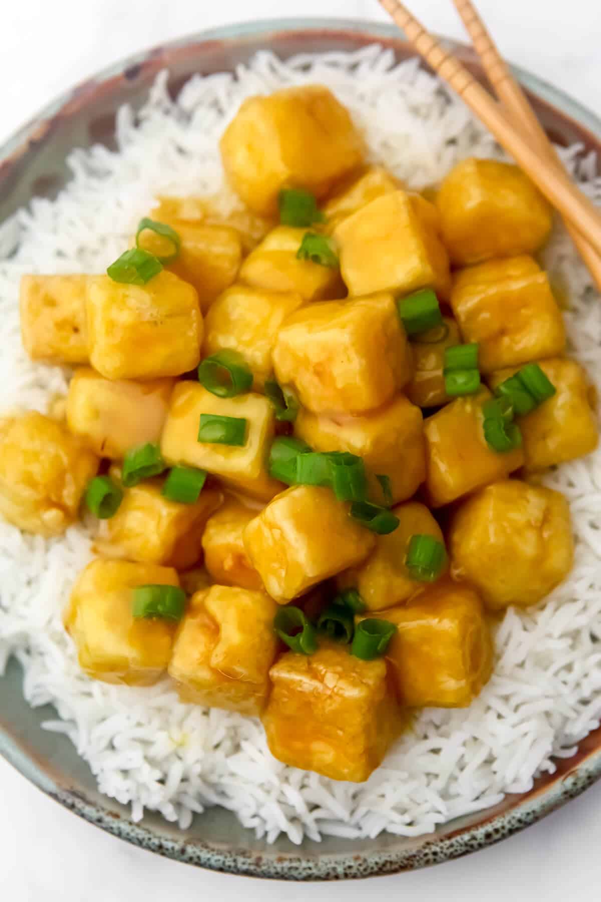 A top view of crispy orange tofu with green onions.