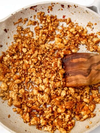 Vegan tofu sausage frying in a pan.