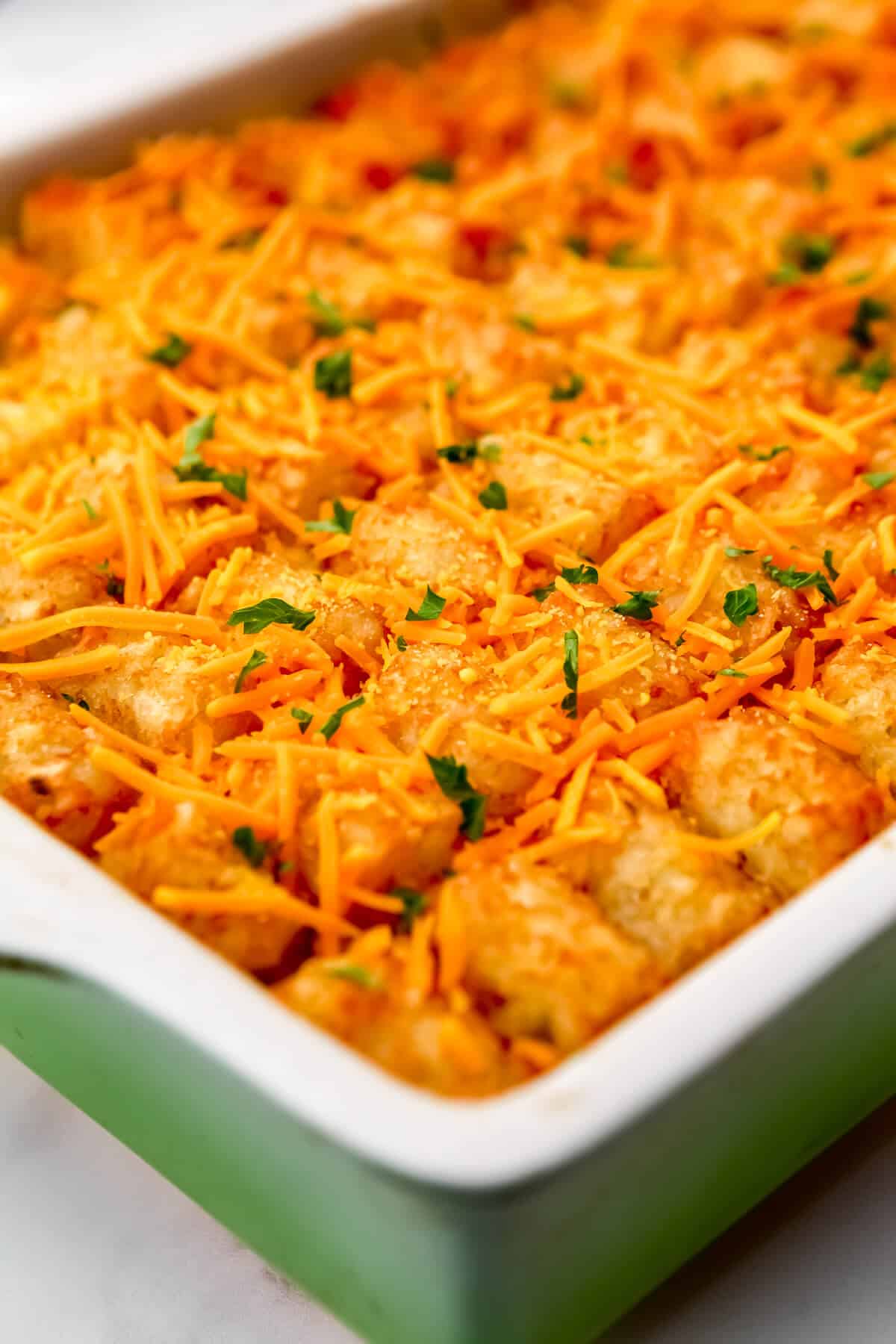 A vegan breakfast casserole topped with tater tots and vegan cheese.