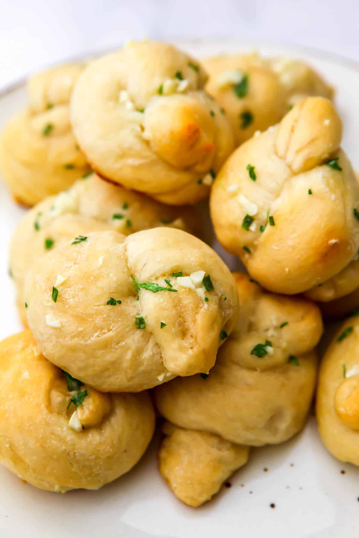 A pile of vegan garlic knots on a white plate.