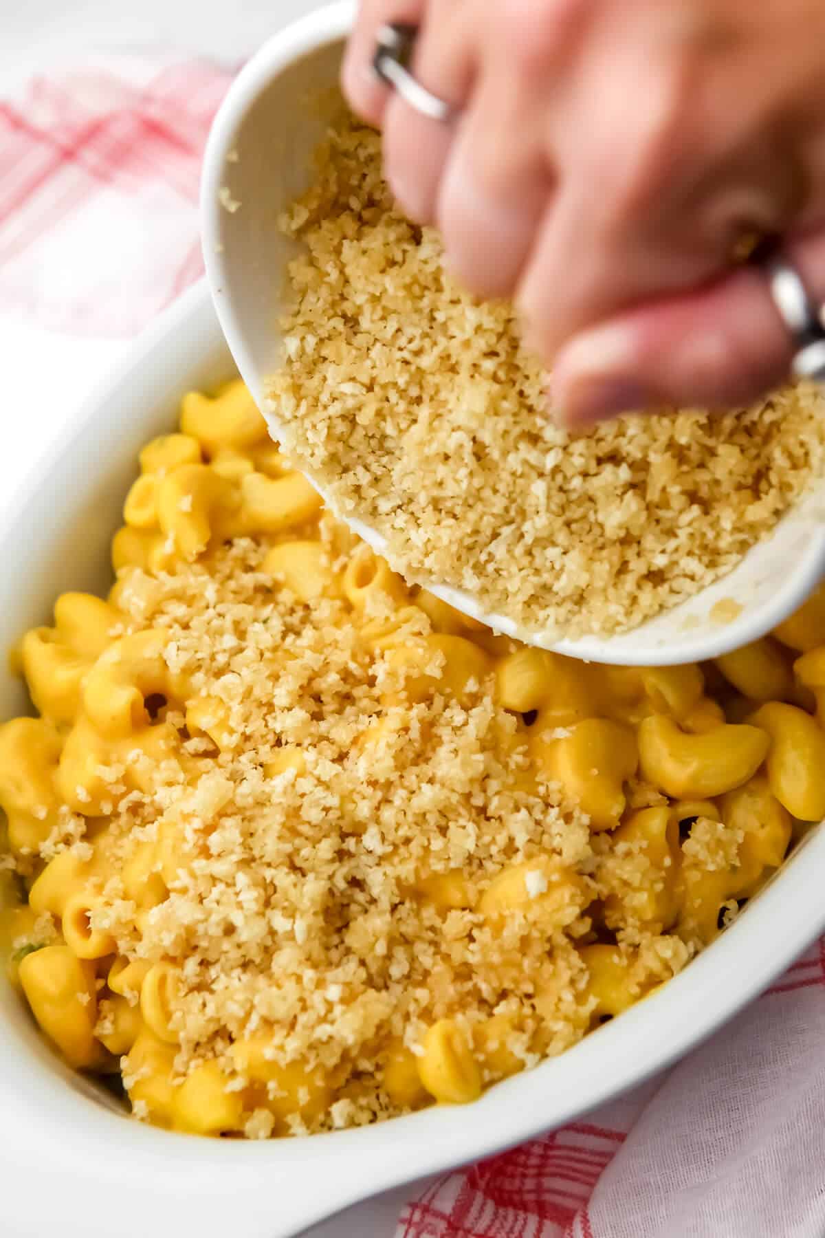 Sprinkling a breadcrumb mixture over the top of vegan mac and cheese before baking.
