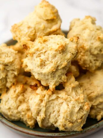 Vegan drop biscuits stacked on a plate.
