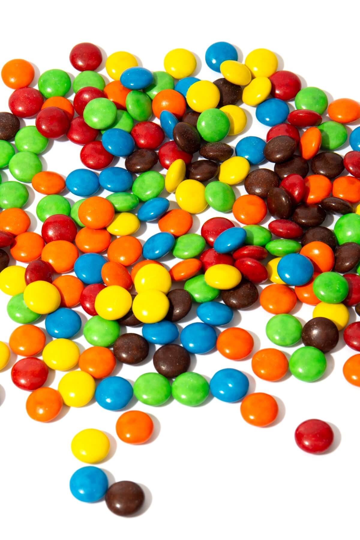 Colorful M&Ms spilled out on a white counter top.