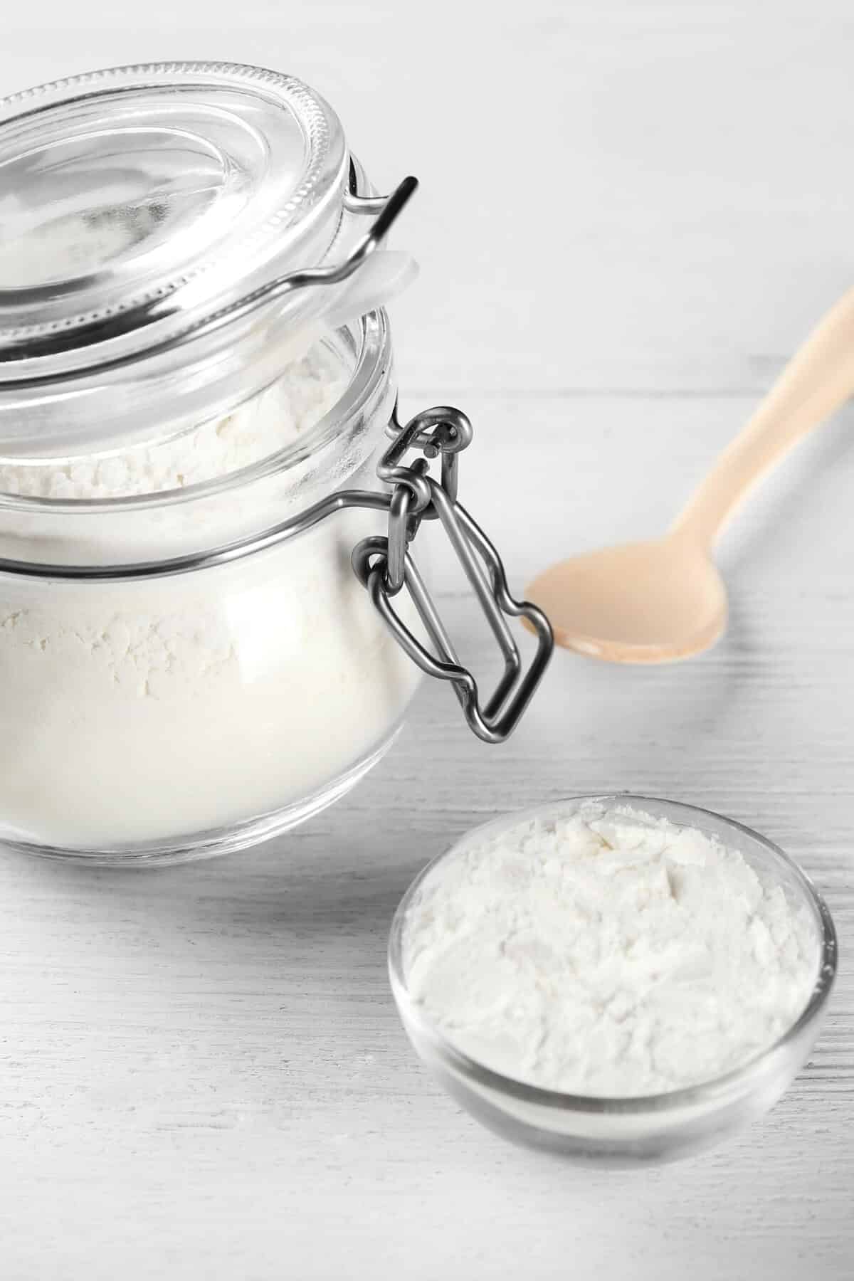 A mason jar and a small bowl filled with cream of tartar.