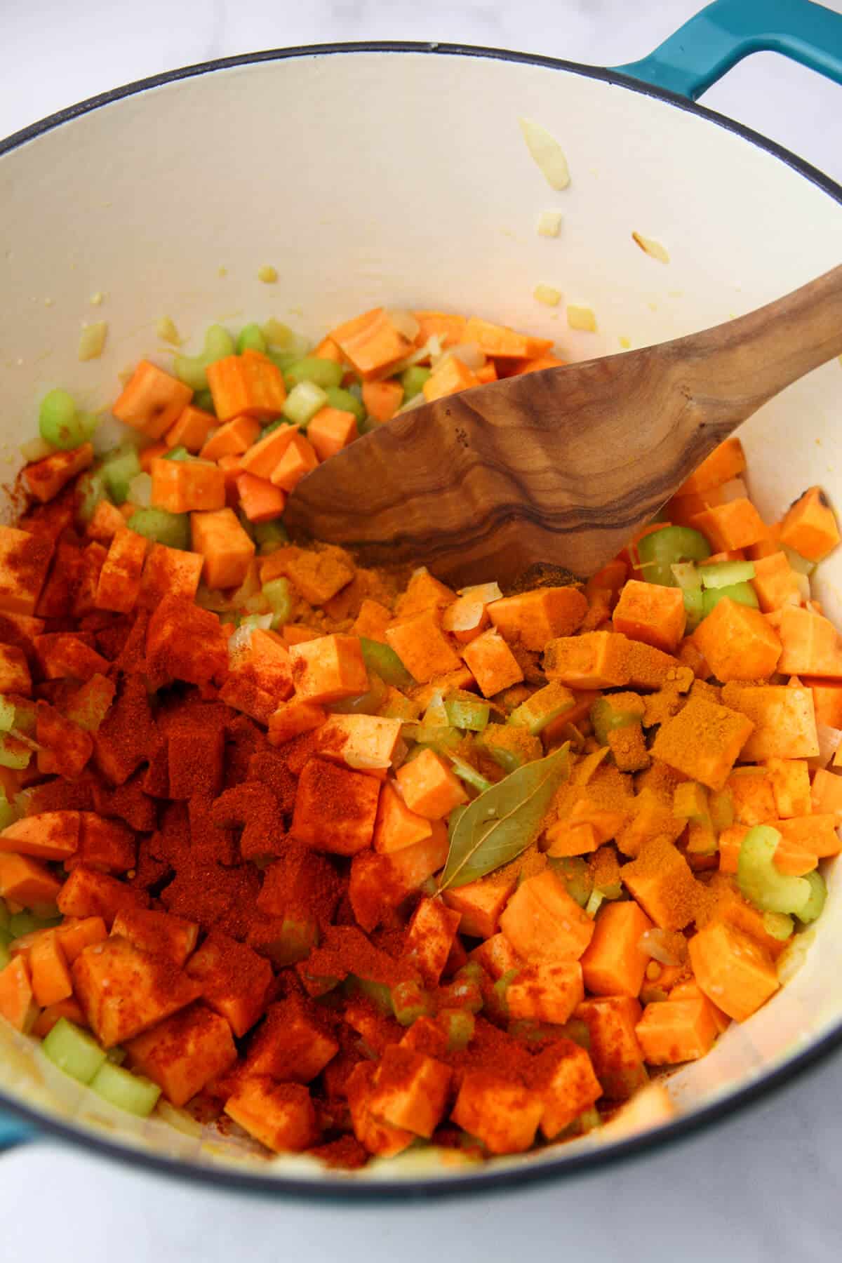 Sweet potatoes and vegetable simmering in a soup pot with spices.