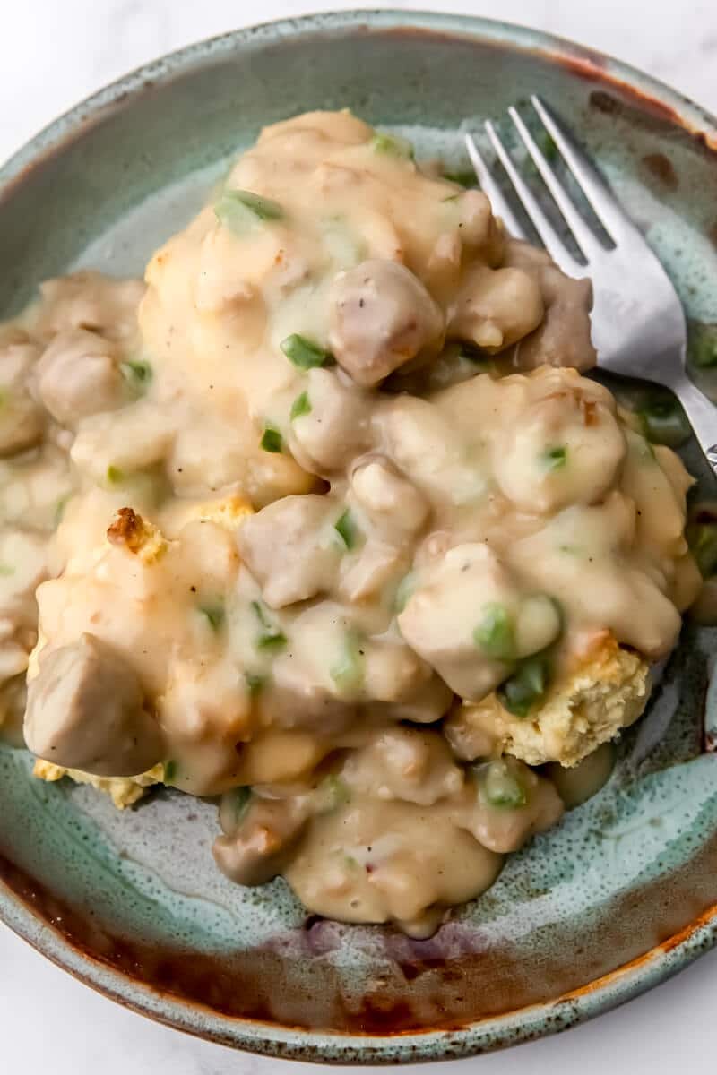 Vegan sausage gravy served over biscuits on a green plate.