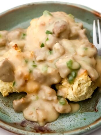 A plate filled with vegan biscuits and gravy with a fork on the side.