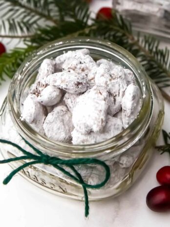 A mason jar filled with cinnamon and sugar coved vegan candied pecans.