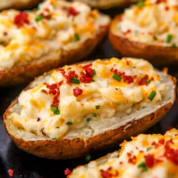 Vegan twice baked potatoes stuffed with cheesy vegan mashed potatoes and toped with bacon bits and chives.