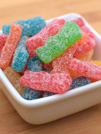 A small white bowl filled with sour patch kids candies.