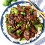 A top view of a blue plate filled with rice topped with vegan beef and broccoli.