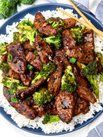 A top view of a blue plate filled with rice topped with vegan beef and broccoli.
