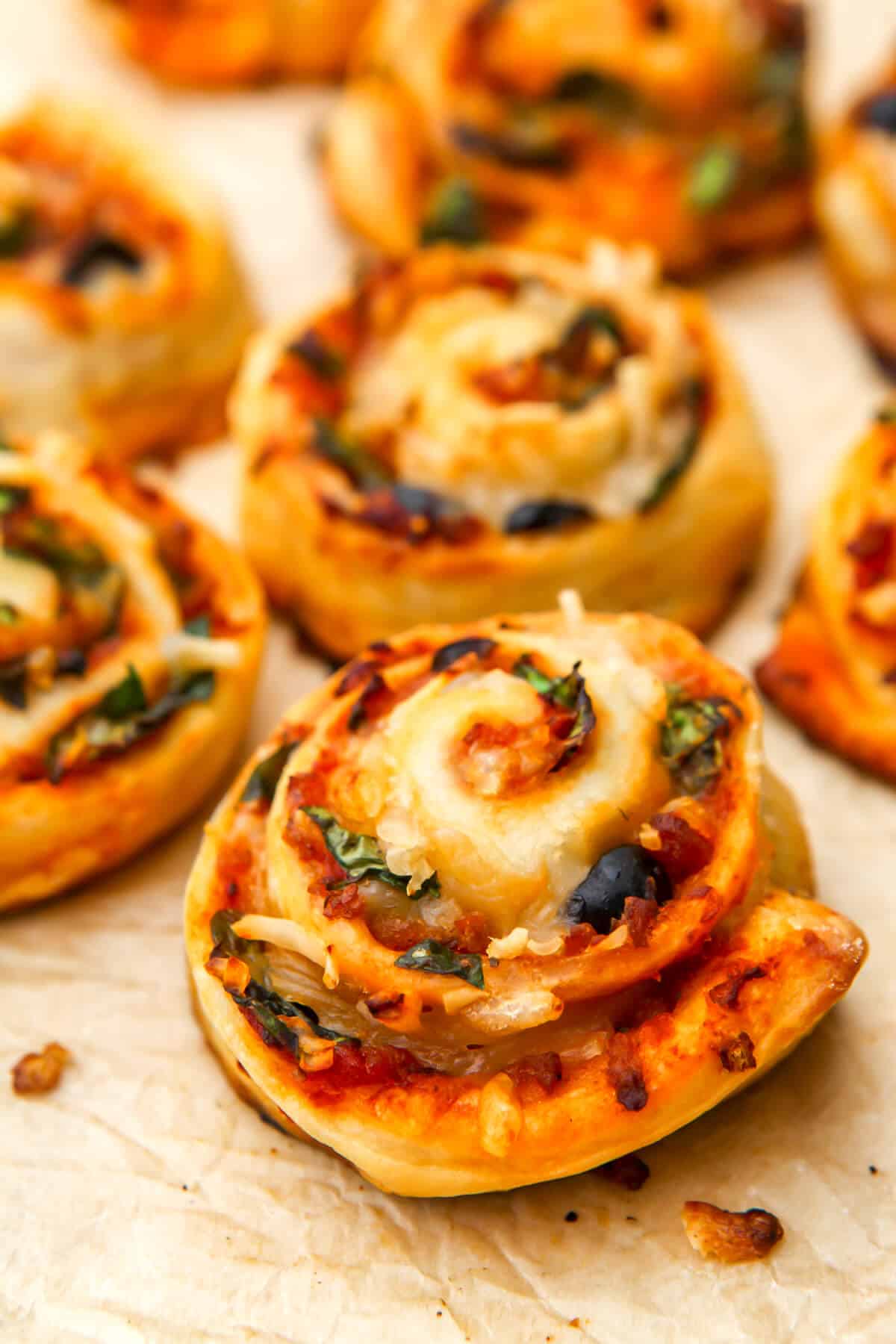 A close up of vegan pizza pinwheels on parchment paper.