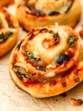 Vegan pizza rolls on a piece of brown parchment paper.