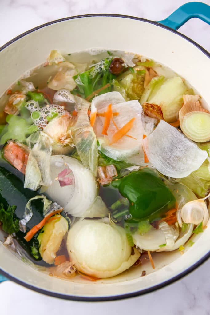 A soup pot full of vegetable scraps and water to make homemade broth.