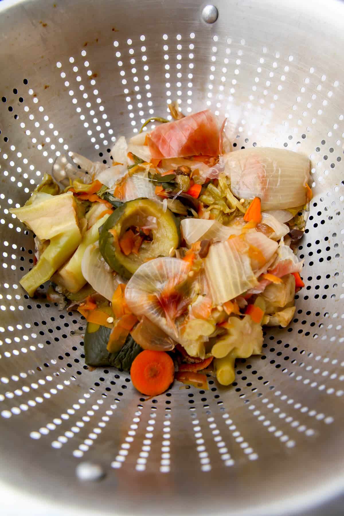 Vegetable scraps in a strainer after they have been boiled down to make broth.