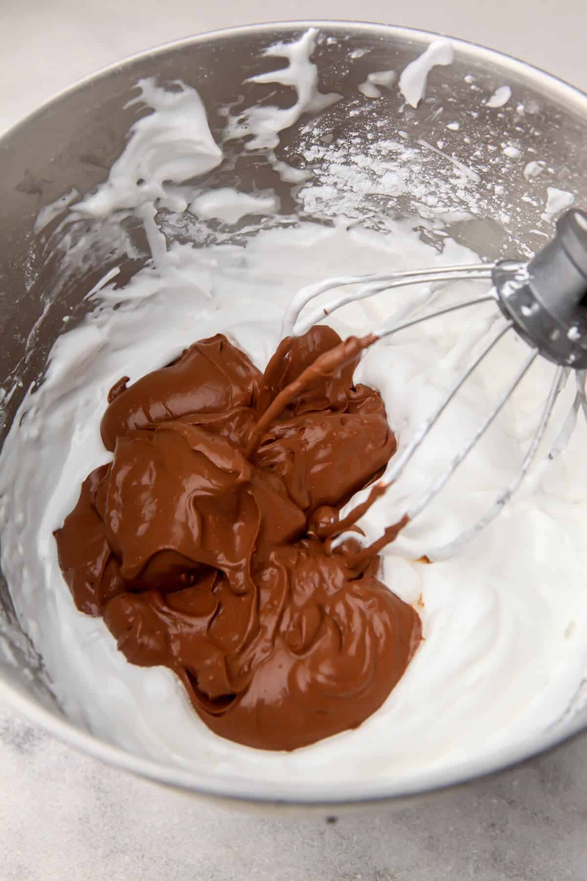 Blended chocolate being added to aquafaba to make vegan chocolate mousse.