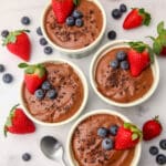 A top view of four bowls of vegan silken tofu chocolate mousse with berries on top.
