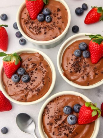 A top view of four bowls of vegan silken tofu chocolate mousse with berries on top.