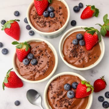 A top view of four bowls of vegan silken tofu chocolate mousse with berries on top.