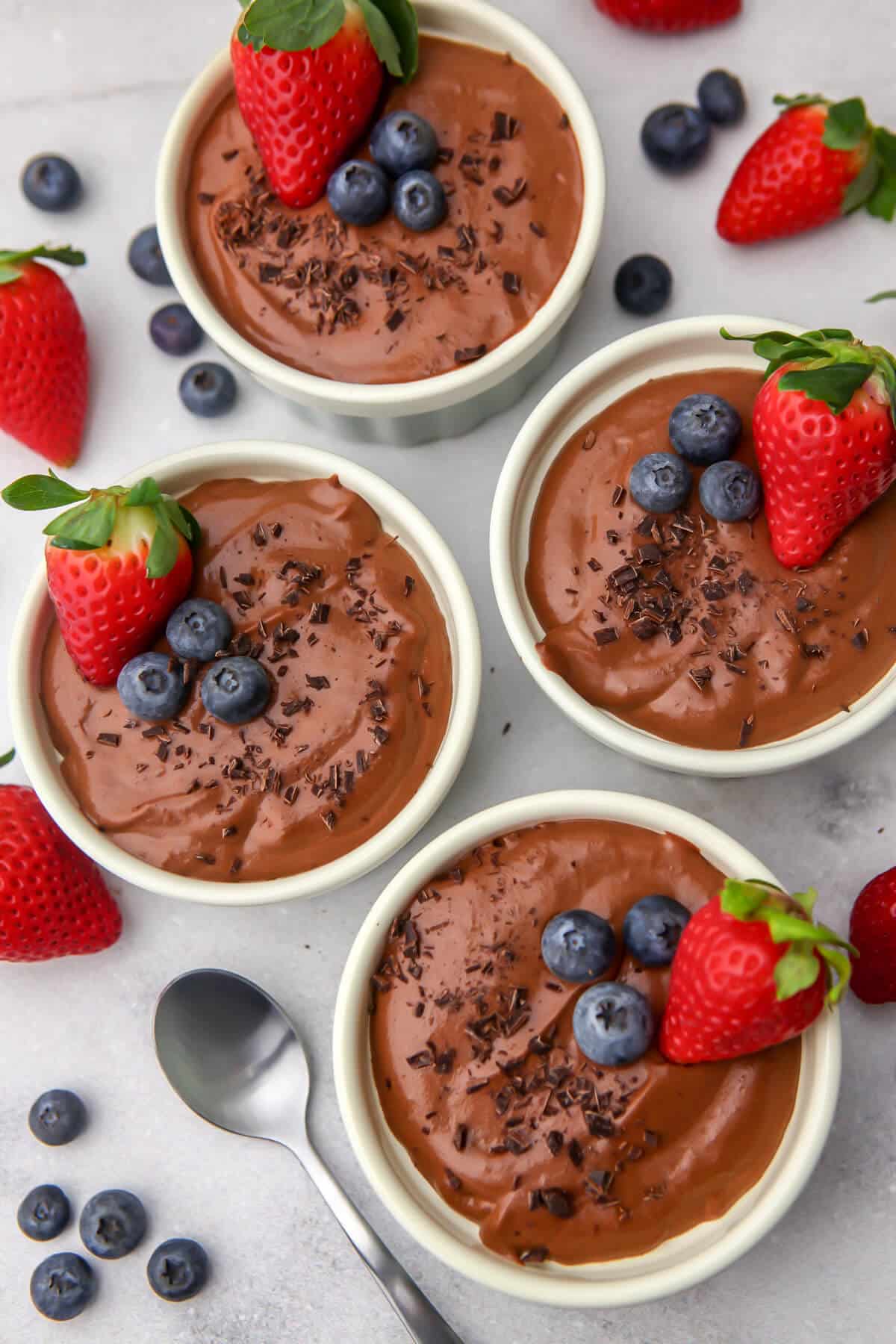 A top view of 4 ramekins of silken tofu chocolate mousse with berries on top.