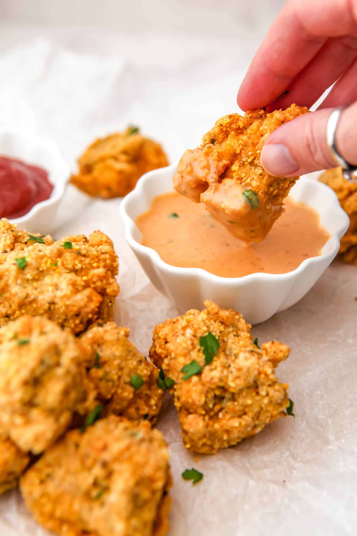 Vegan tofu fried chicken being dunked in vegan Chick Fil A sauce.