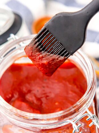 Vegan bbq sauce in a jar with sauce on a brush.